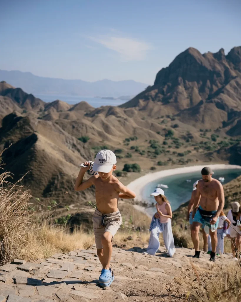 Young boy climbing the wooden trail with family on Padar Island.