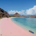 Close-up view of soft pink sands blending with clear blue waters.
