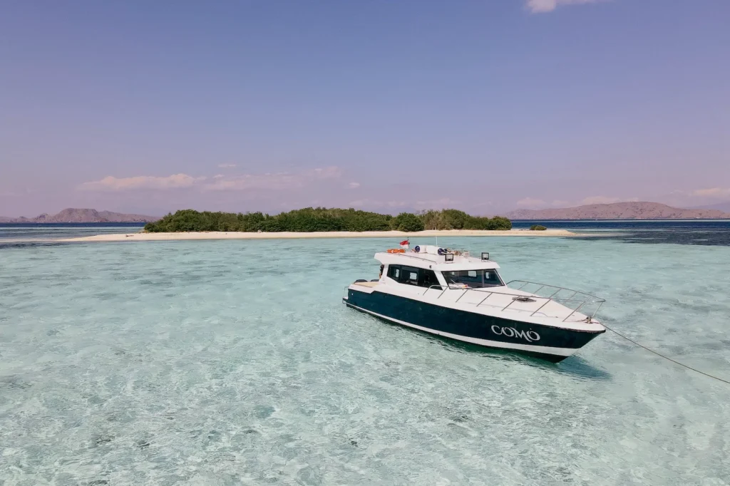 Como boat parked in front of a remote white sand island in the middle of a tour for the best places to visit in Komodo National Park
