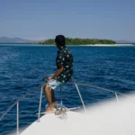 Man seated on the front deck of Athar as they approach a quiet, empty island in Komodo.