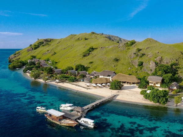 Sebayur Island dock near Komodo Resort with white sand beach, boats, and coral-rich waters