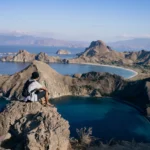 Man standing solo at hilltop on Padar with panoramic backdrop.