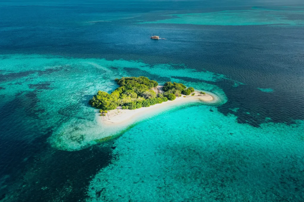 Aerial shot of small island near Taka Makassar with visible coral beds.